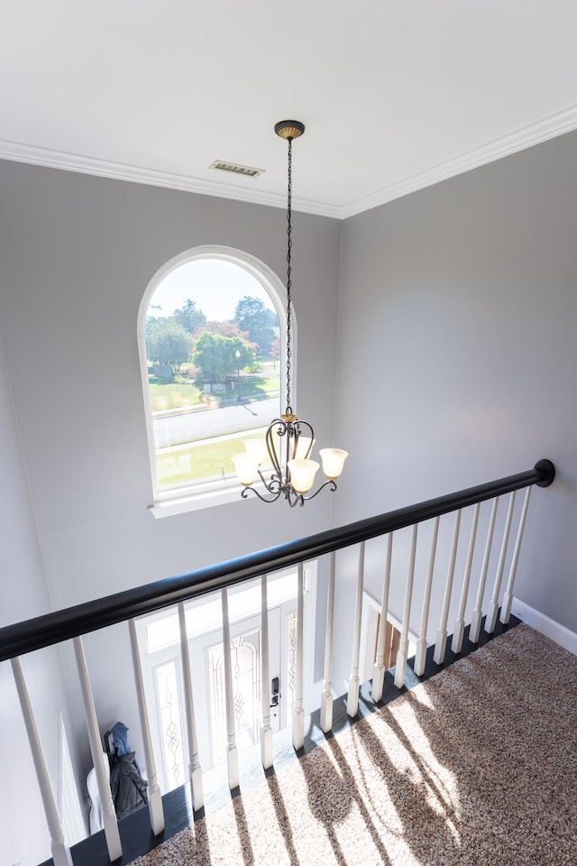 stairway featuring ornamental molding, a chandelier, and carpet