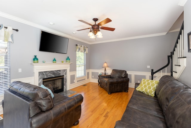 living room with a premium fireplace, ornamental molding, wood-type flooring, and plenty of natural light