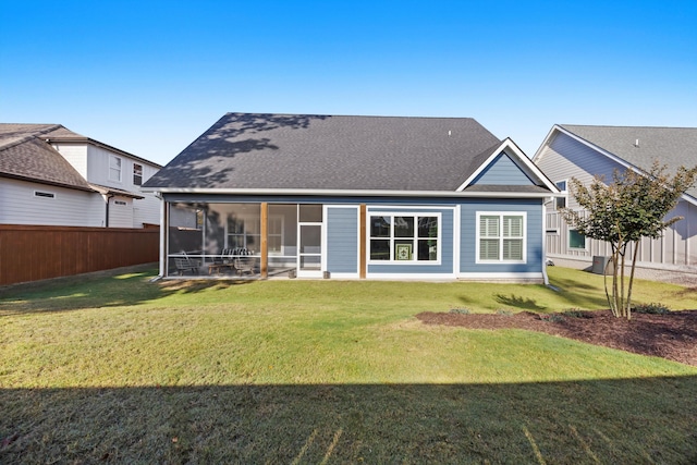 rear view of house featuring a lawn and a sunroom