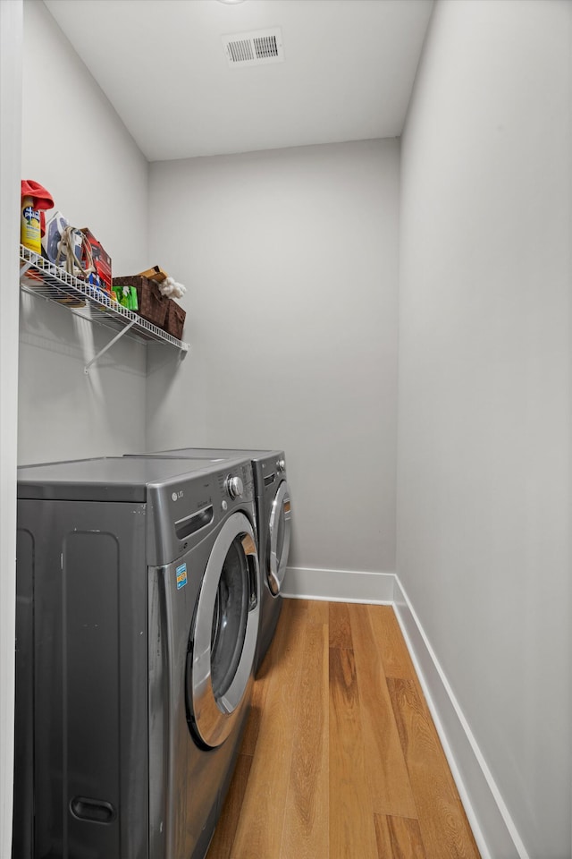 clothes washing area with hardwood / wood-style flooring and separate washer and dryer