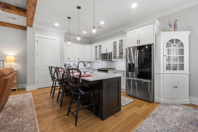 kitchen with white cabinetry, appliances with stainless steel finishes, a kitchen bar, and a center island with sink