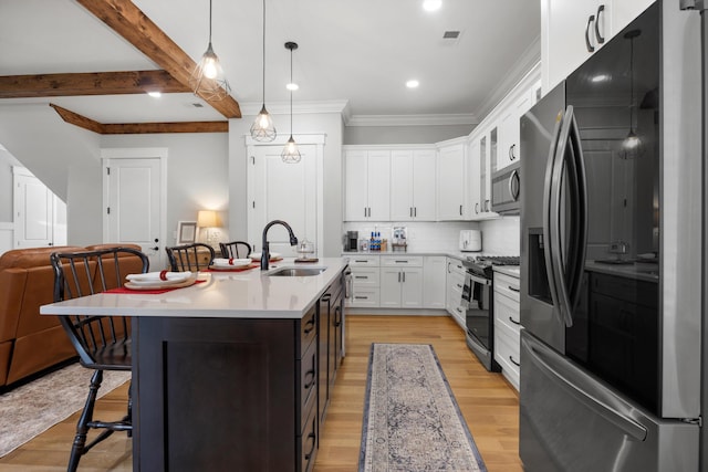 kitchen with white cabinetry, an island with sink, sink, hanging light fixtures, and stainless steel appliances