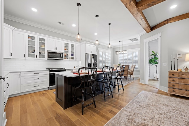 kitchen with white cabinetry, hanging light fixtures, a kitchen breakfast bar, stainless steel appliances, and a center island