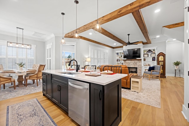 kitchen featuring dishwasher, sink, pendant lighting, and an island with sink