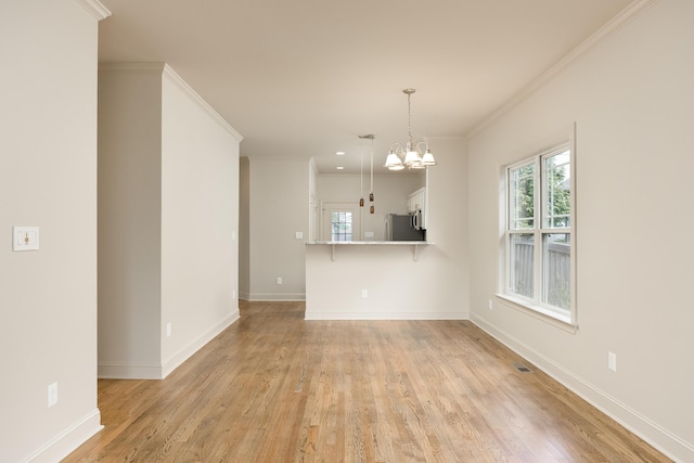 unfurnished living room with light hardwood / wood-style floors, crown molding, and a notable chandelier