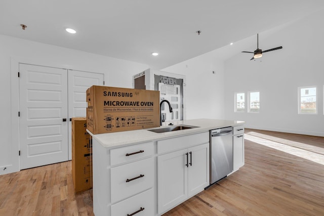 kitchen with stainless steel dishwasher, sink, white cabinets, light hardwood / wood-style floors, and an island with sink