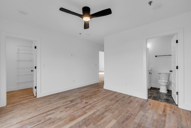 unfurnished bedroom featuring a walk in closet, a closet, ensuite bath, and light wood-type flooring