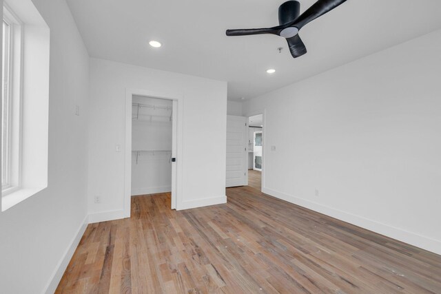 unfurnished bedroom with a walk in closet, ceiling fan, a closet, and light hardwood / wood-style floors