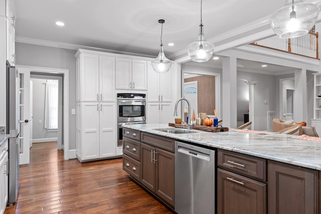 kitchen featuring dark wood-type flooring, white cabinets, hanging light fixtures, sink, and appliances with stainless steel finishes