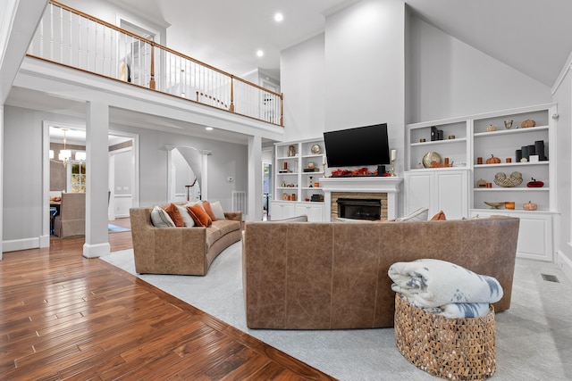 living room featuring hardwood / wood-style flooring, a fireplace, high vaulted ceiling, and an inviting chandelier