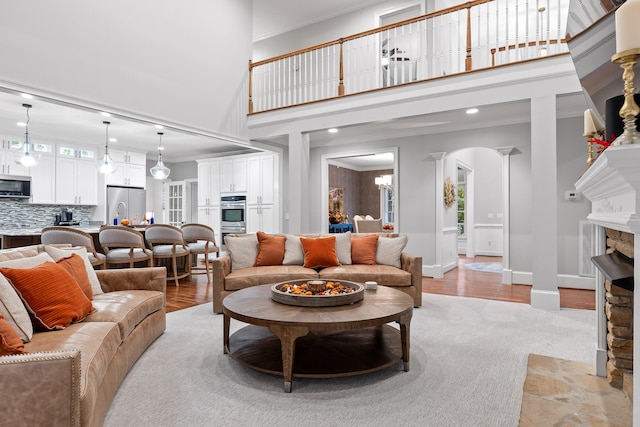 living room featuring ornamental molding, a fireplace, a high ceiling, and light hardwood / wood-style flooring