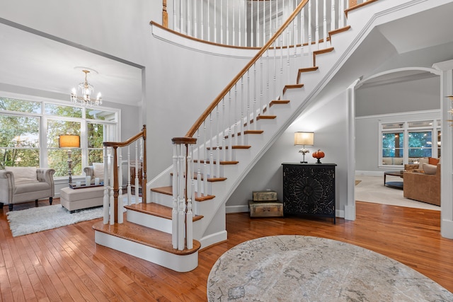 stairway featuring hardwood / wood-style flooring, a high ceiling, and a chandelier