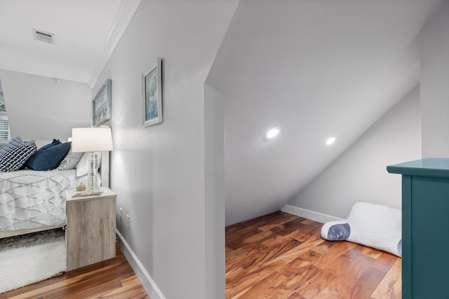 interior space featuring hardwood / wood-style floors, vaulted ceiling, and ornamental molding