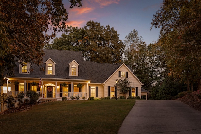 cape cod-style house featuring a lawn and covered porch