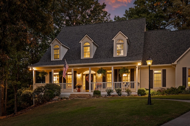 cape cod home featuring a lawn and a porch