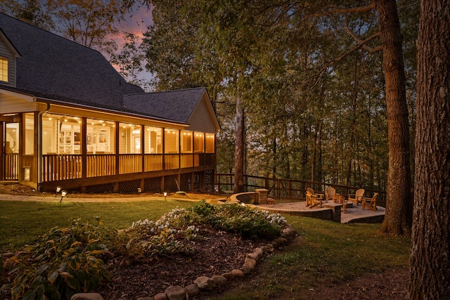 exterior space with a sunroom, a patio area, a yard, and an outdoor fire pit