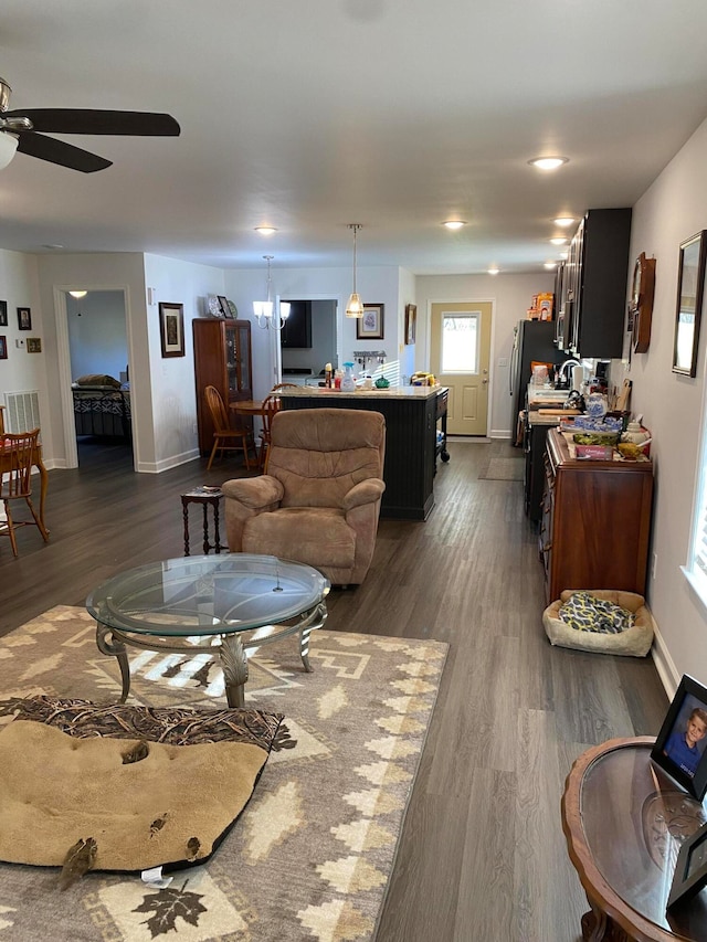 living room featuring ceiling fan with notable chandelier and dark hardwood / wood-style flooring