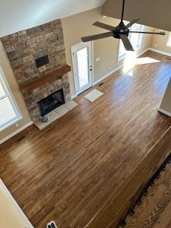 unfurnished living room featuring a fireplace, dark hardwood / wood-style floors, vaulted ceiling, and ceiling fan