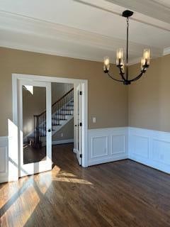 unfurnished dining area with crown molding, french doors, dark hardwood / wood-style floors, and a notable chandelier