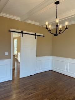 spare room featuring dark hardwood / wood-style flooring, a barn door, ornamental molding, and a notable chandelier