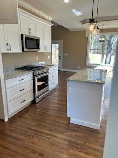 kitchen with white cabinetry, pendant lighting, light stone counters, and appliances with stainless steel finishes