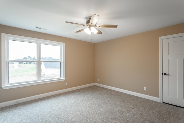 carpeted empty room with a ceiling fan, visible vents, and baseboards