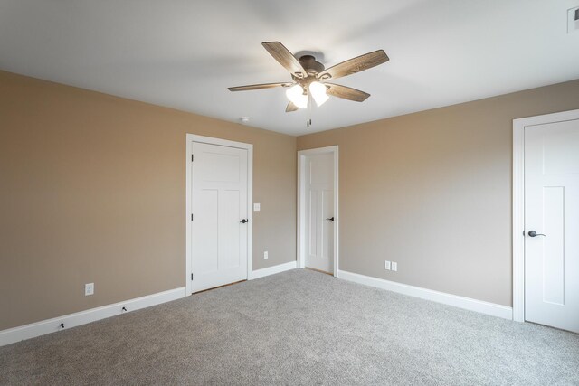 empty room with a ceiling fan, carpet, visible vents, and baseboards