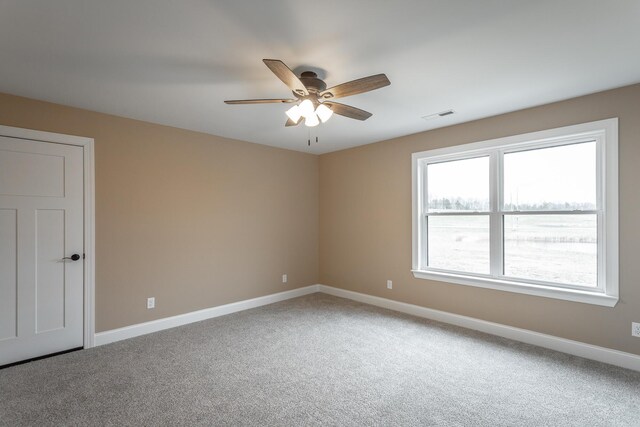 carpeted empty room with baseboards, visible vents, and a ceiling fan