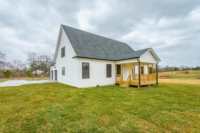 rear view of property with a garage, a shingled roof, concrete driveway, crawl space, and a yard