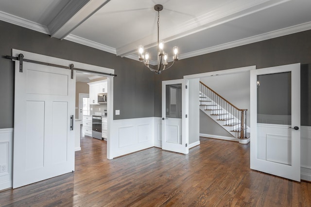 unfurnished dining area featuring a wainscoted wall, dark wood-style flooring, a barn door, and beamed ceiling