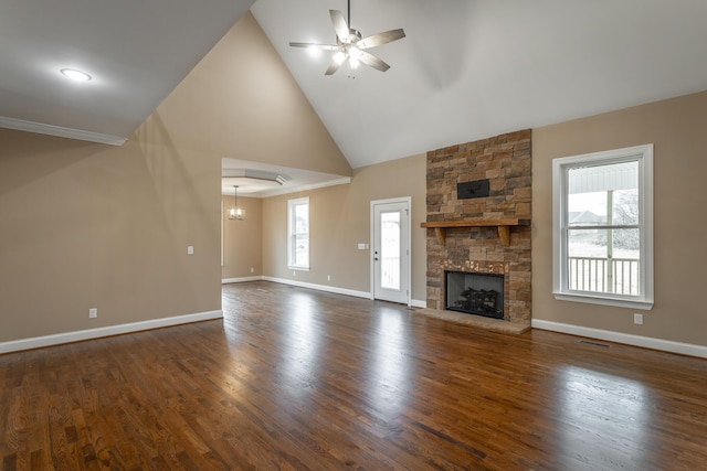 unfurnished living room with a ceiling fan, a wealth of natural light, dark wood finished floors, and a stone fireplace