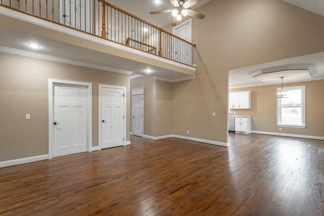 unfurnished living room featuring ornamental molding, dark wood finished floors, a high ceiling, and baseboards