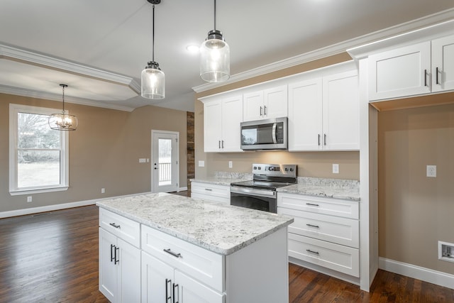 kitchen with appliances with stainless steel finishes, dark wood-type flooring, ornamental molding, white cabinets, and a kitchen island