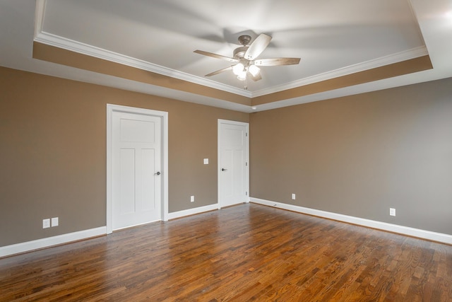 unfurnished room with a tray ceiling, crown molding, dark wood finished floors, a ceiling fan, and baseboards