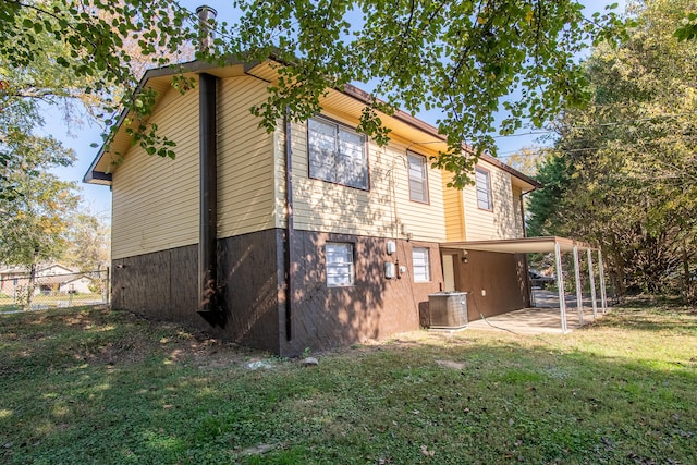 rear view of property featuring a lawn and central AC unit