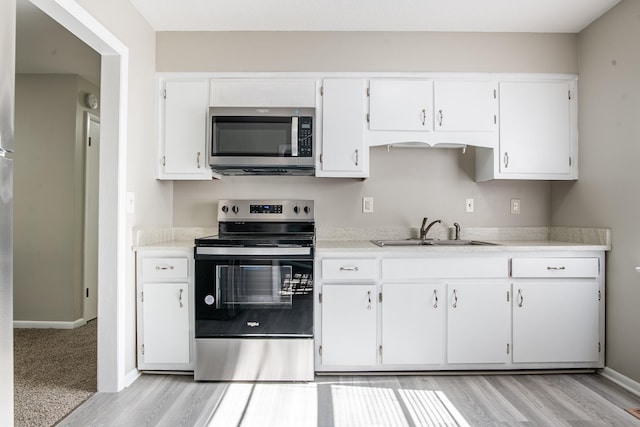 kitchen featuring sink, appliances with stainless steel finishes, light wood-type flooring, and white cabinets