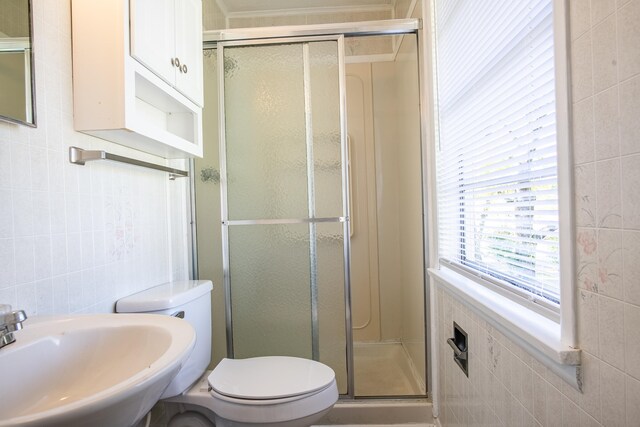 bathroom with toilet, tile walls, sink, and an enclosed shower