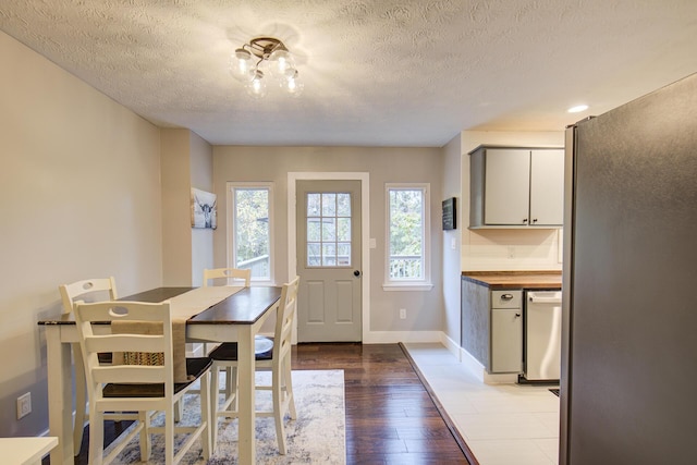 dining space featuring a textured ceiling, light wood-type flooring, and baseboards