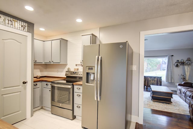 kitchen with appliances with stainless steel finishes, wood counters, open floor plan, and recessed lighting