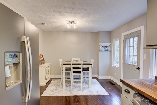 dining space with dark wood finished floors, a textured ceiling, and baseboards