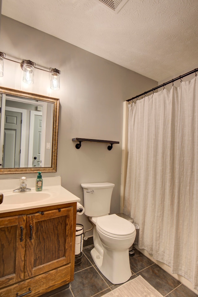 bathroom with a textured ceiling, toilet, vanity, curtained shower, and tile patterned floors