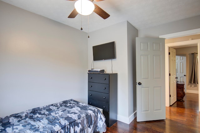 bedroom with a textured ceiling, dark wood-type flooring, and ceiling fan