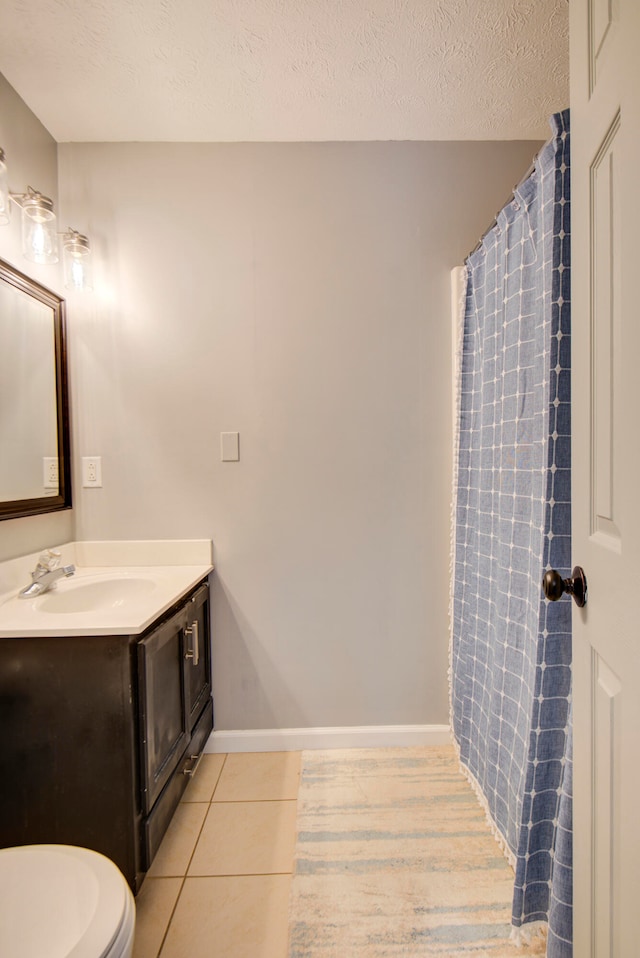 bathroom featuring vanity, toilet, tile patterned floors, and a textured ceiling