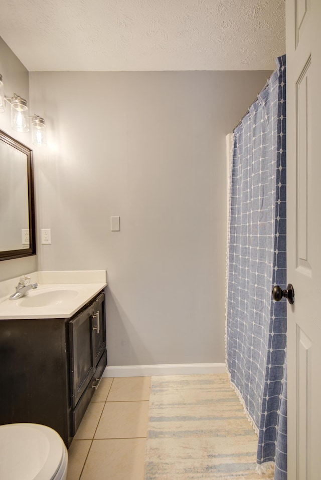 bathroom featuring vanity, tile patterned flooring, toilet, and a textured ceiling