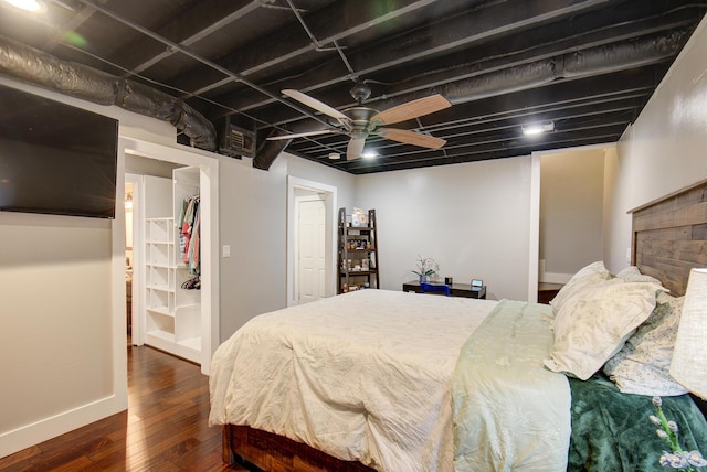 bedroom featuring dark wood finished floors, a walk in closet, a ceiling fan, a closet, and baseboards
