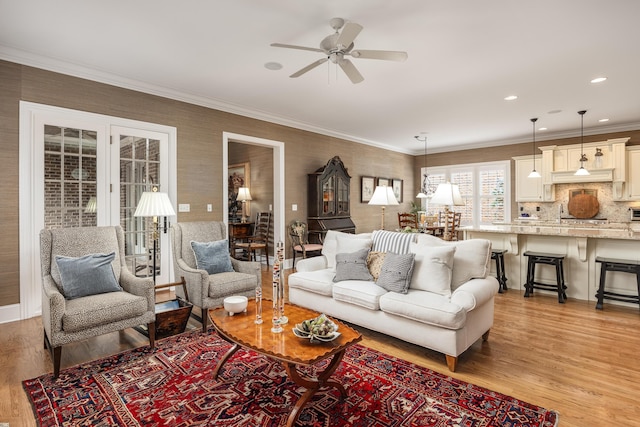 living room with ceiling fan, crown molding, and light hardwood / wood-style flooring