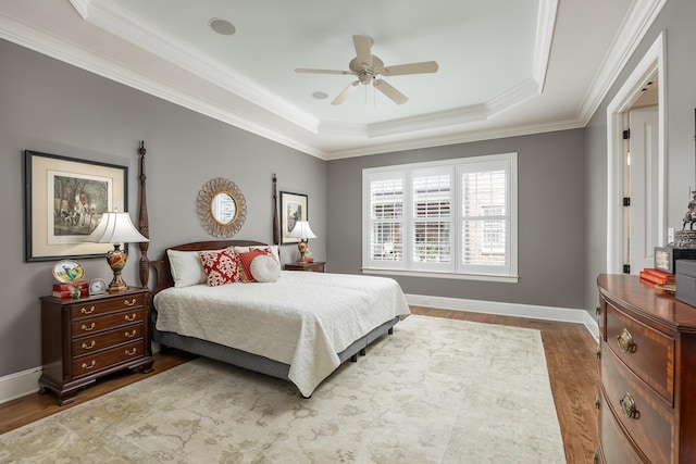 bedroom featuring ceiling fan, dark wood-type flooring, a tray ceiling, and ornamental molding