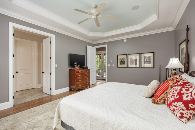 bedroom featuring ceiling fan, light wood-type flooring, crown molding, and a raised ceiling