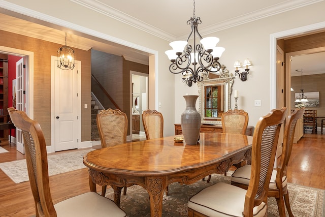 dining space with light wood-type flooring, ornamental molding, and a chandelier