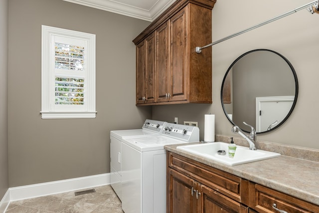 laundry area featuring cabinets, ornamental molding, washer and clothes dryer, and sink